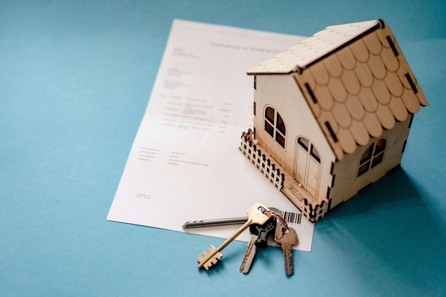 model house and keys on mortgage documents